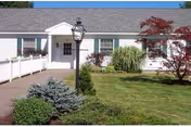Front exterior of Webster at Rye with entrance, lamp post, and manicured shrubs.