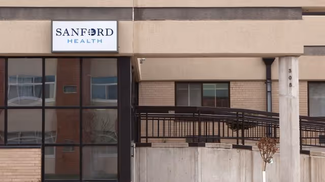 Exterior view of a Sanford Health facility entrance with ramp, glass windows, and sign.