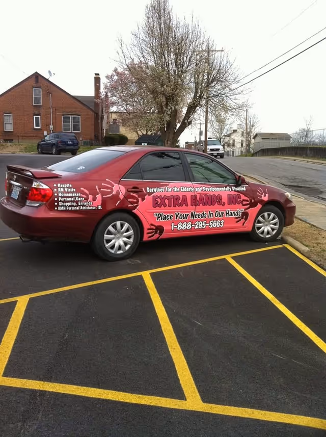 Red Extra Hands promotional car parked in a lot with yellow lines