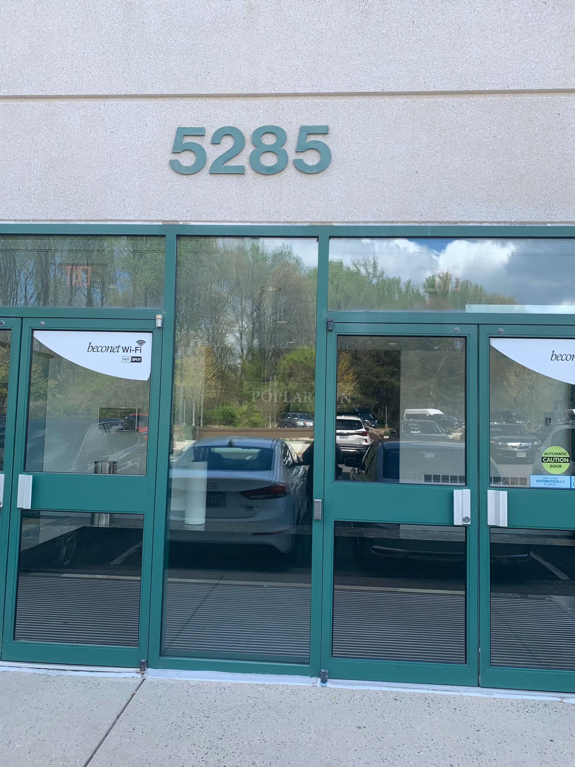 Front entrance of a building with green doors and the number 5285.