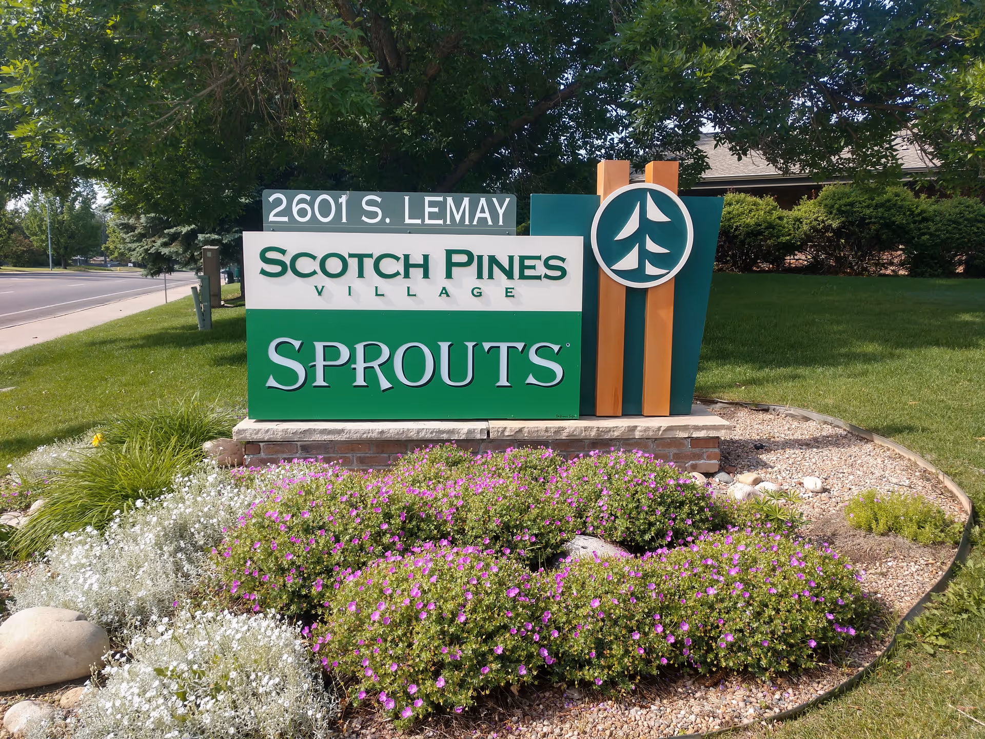Exterior sign for Scotch Pines Village Sprouts with landscaped flower bed
