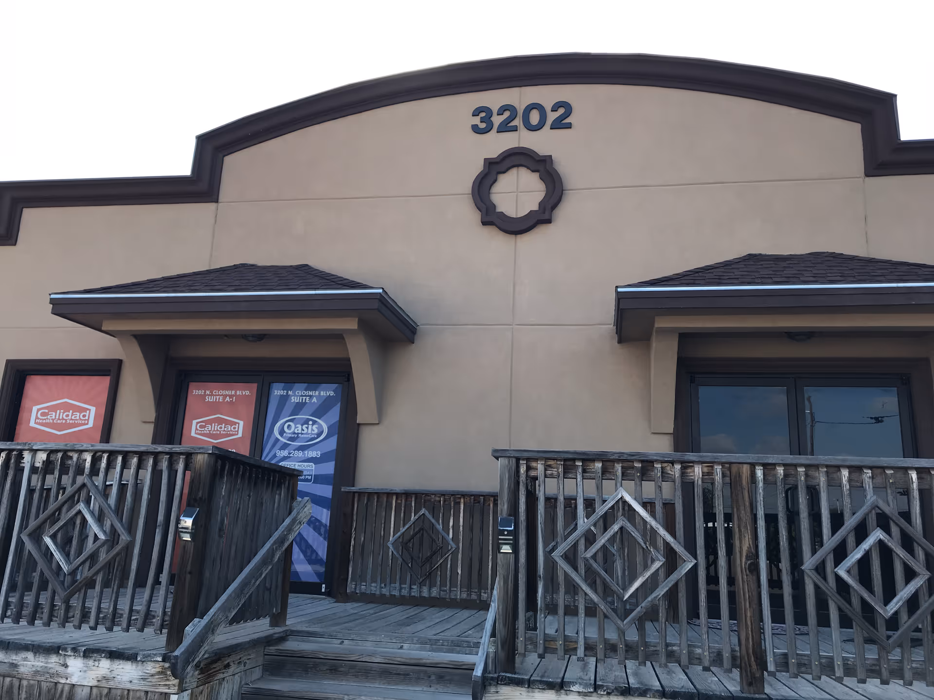 Front of beige building with wooden deck and Oasis banners.