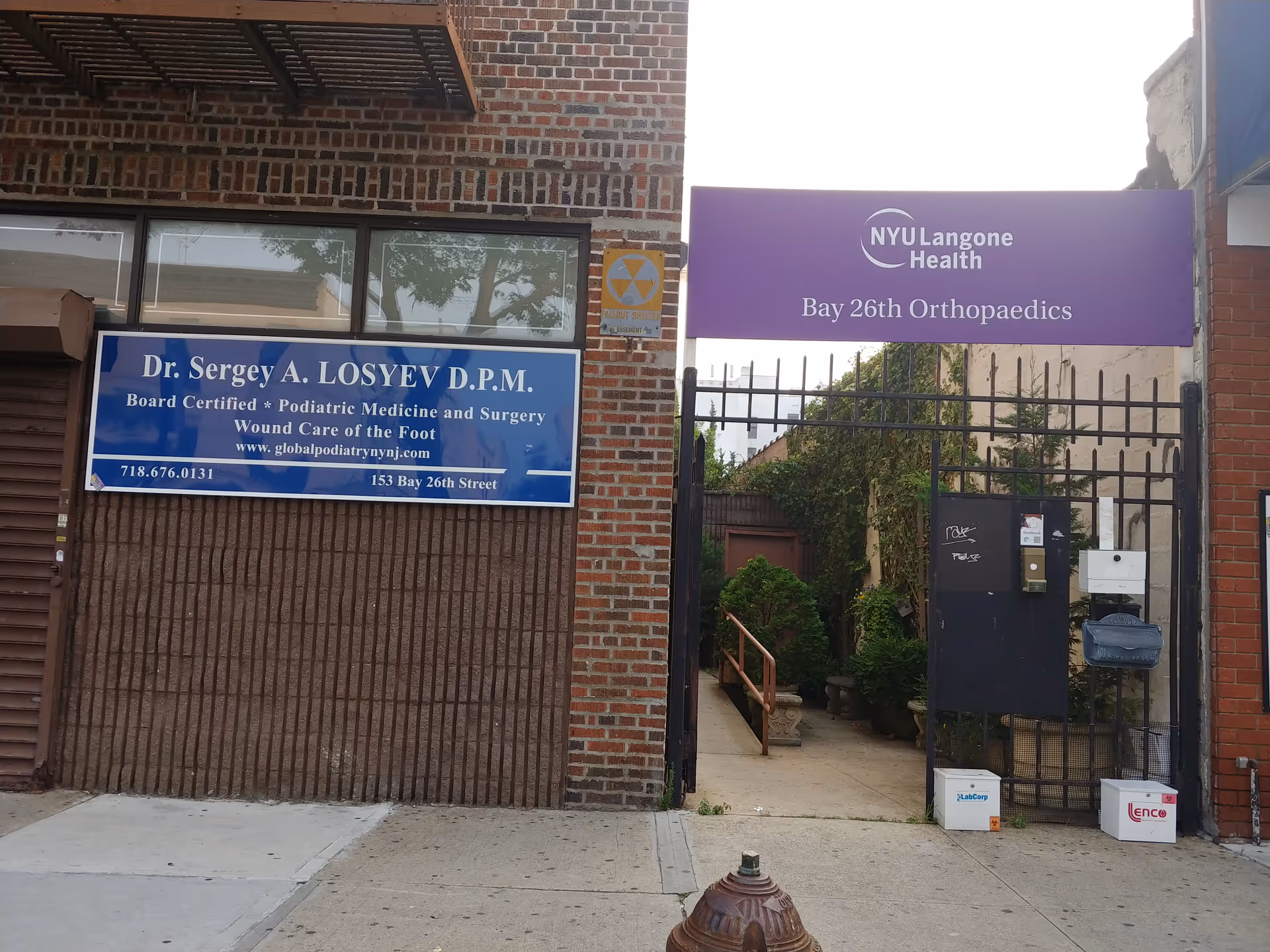 Brick building exterior with a gated entrance and purple NYU Langone Health Bay 26th sign