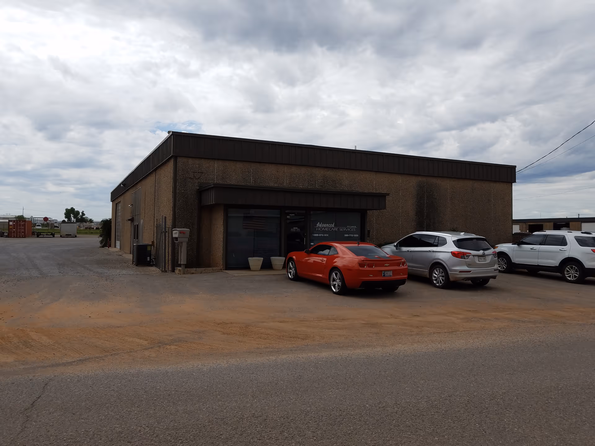Front of a brick building labeled Advanced Home Care Services with parked cars in front