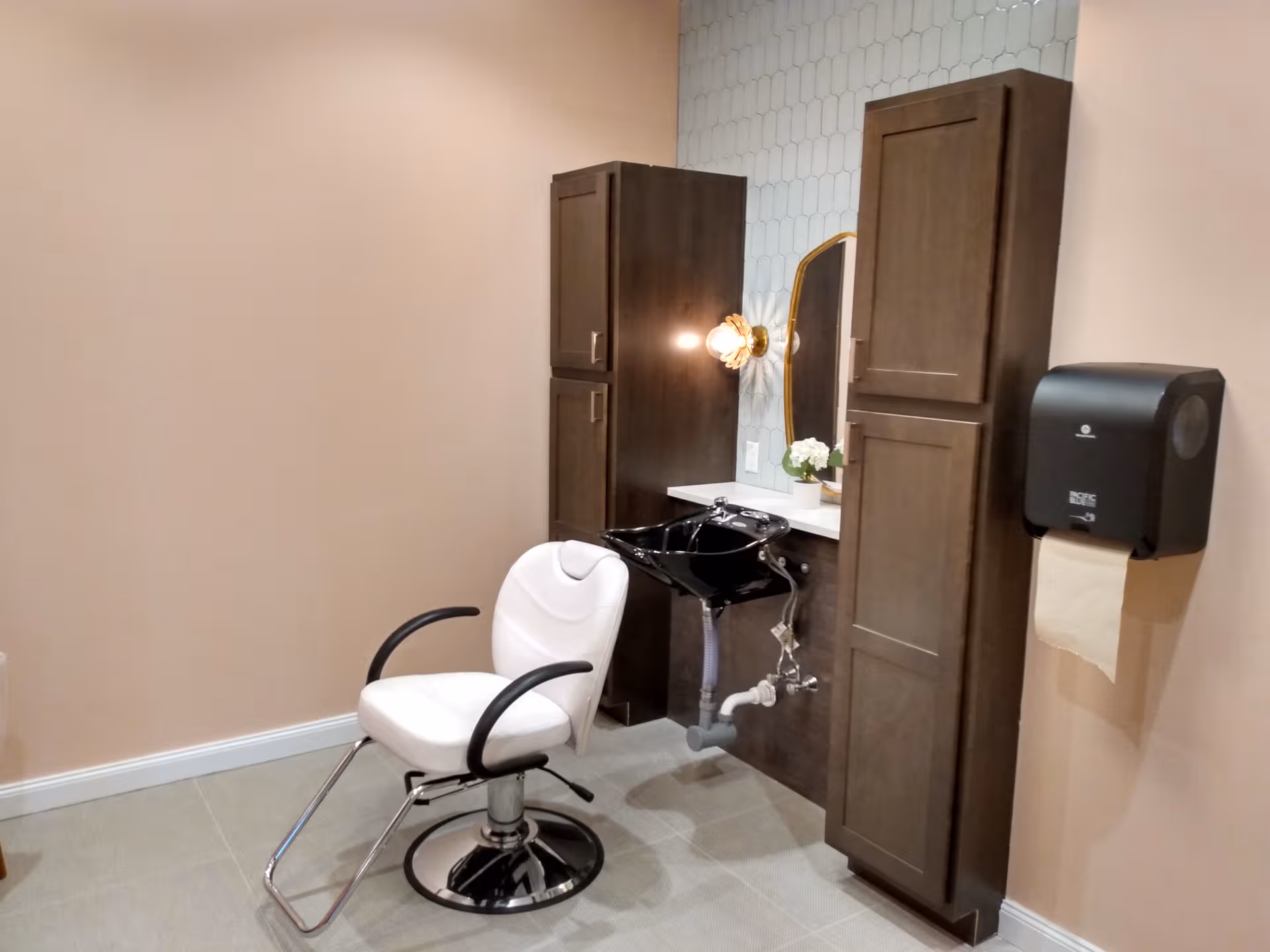 Salon area with styling chair, sink, mirrors, and dark wood cabinets.