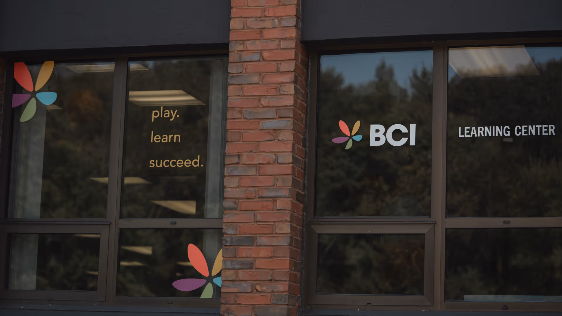 Exterior view of a brick building with BCI Learning Center sign and colorful flower-like logo.