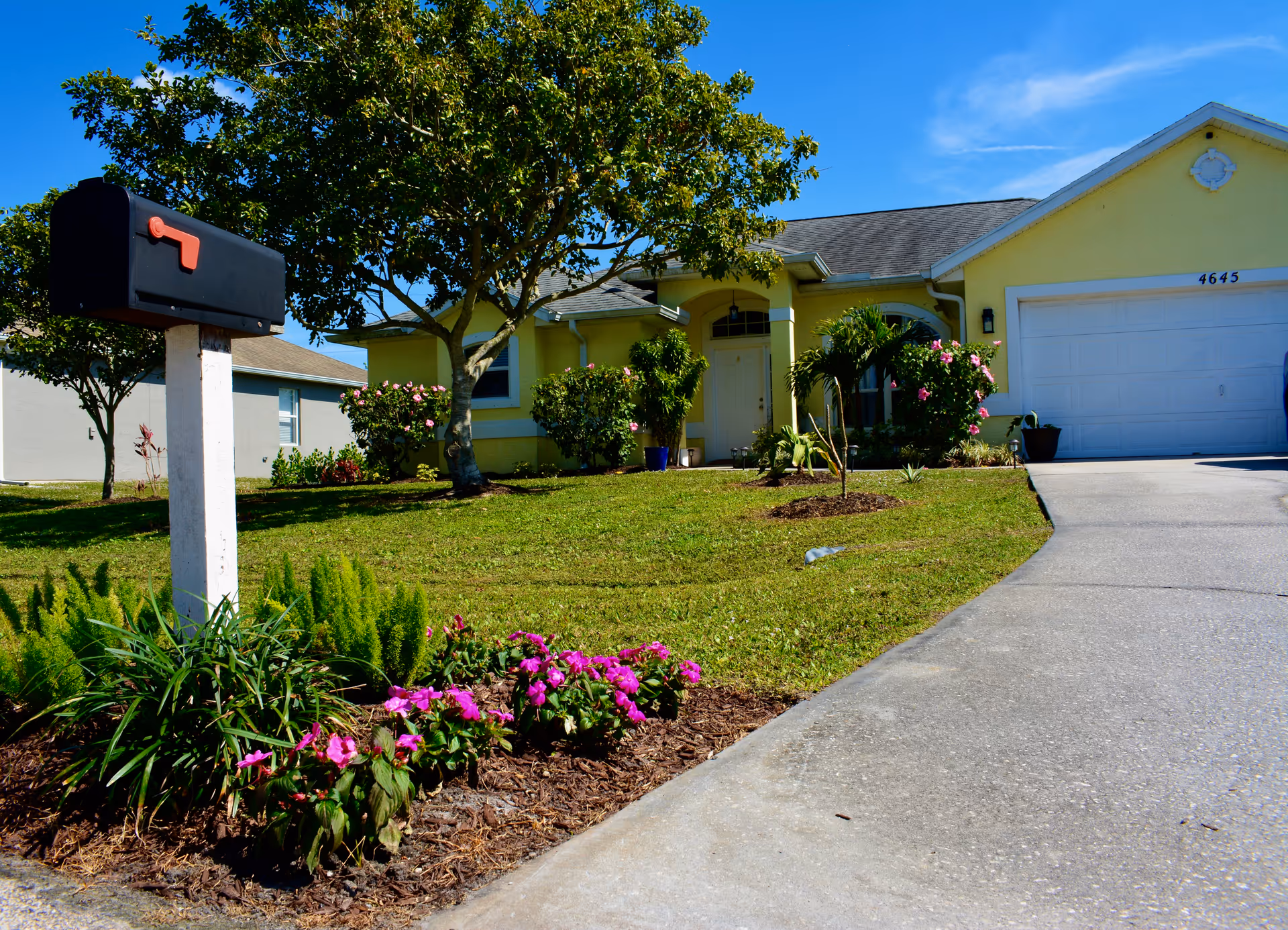 Yellow single-story senior living facility with front yard, driveway, and landscaping.