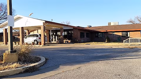 Front entrance of a single-story brick building with a covered drive/portico and a parked car.