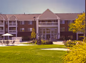Exterior view of Bloomfield senior living facility with green lawn and central entrance.