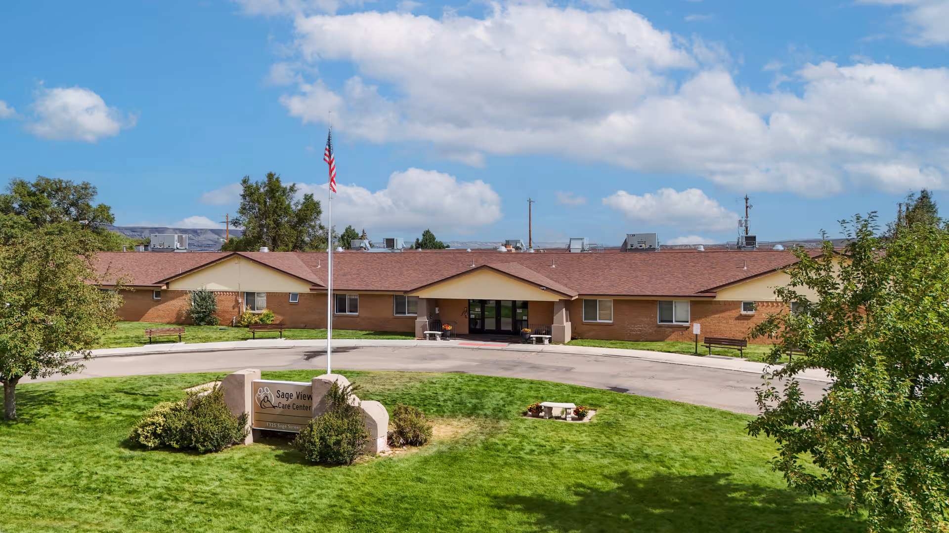 Exterior view of Sage View Care Center entrance with flag and manicured lawn.