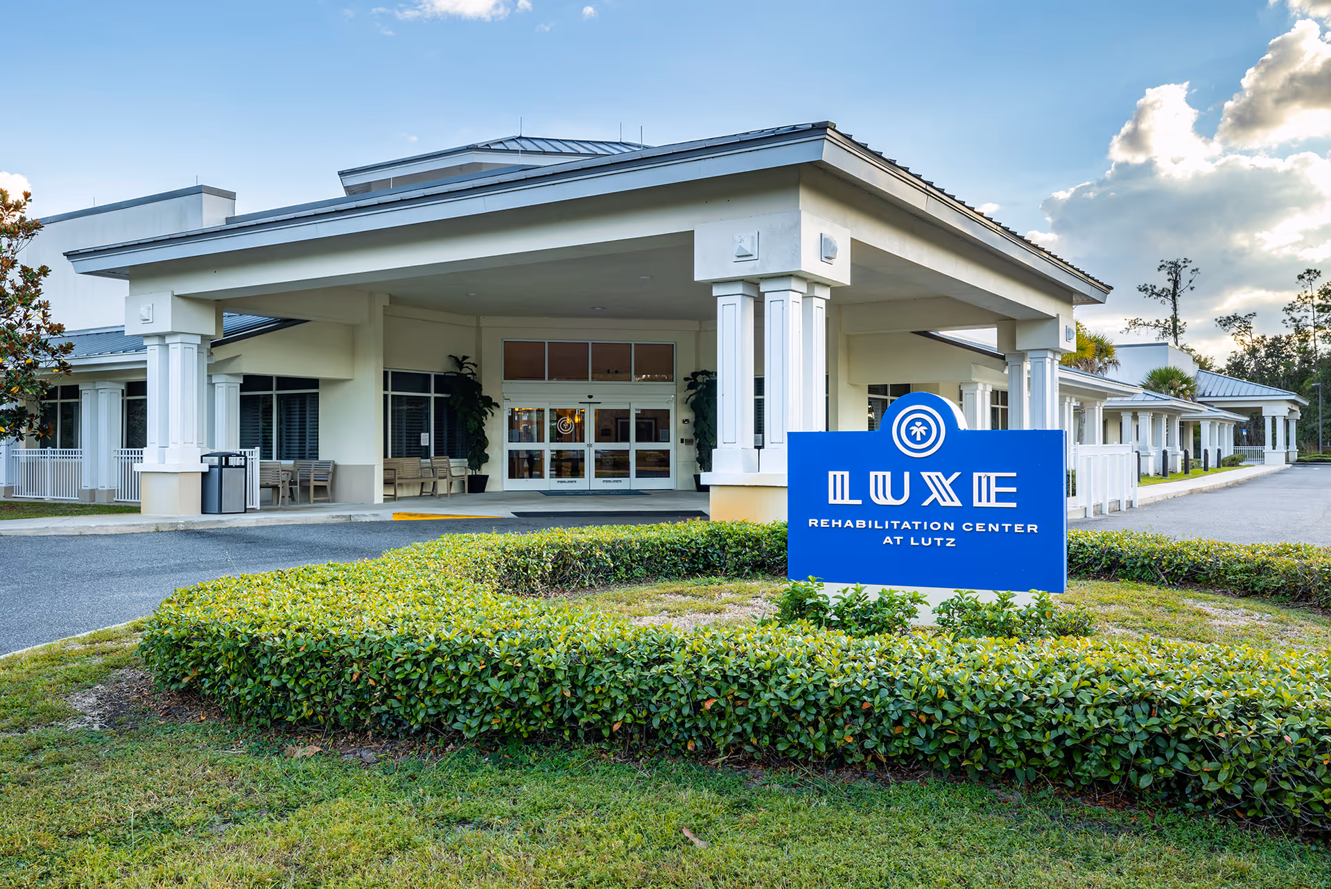 Exterior view of Lutz rehabilitation center entrance with blue sign and porte-cochère.