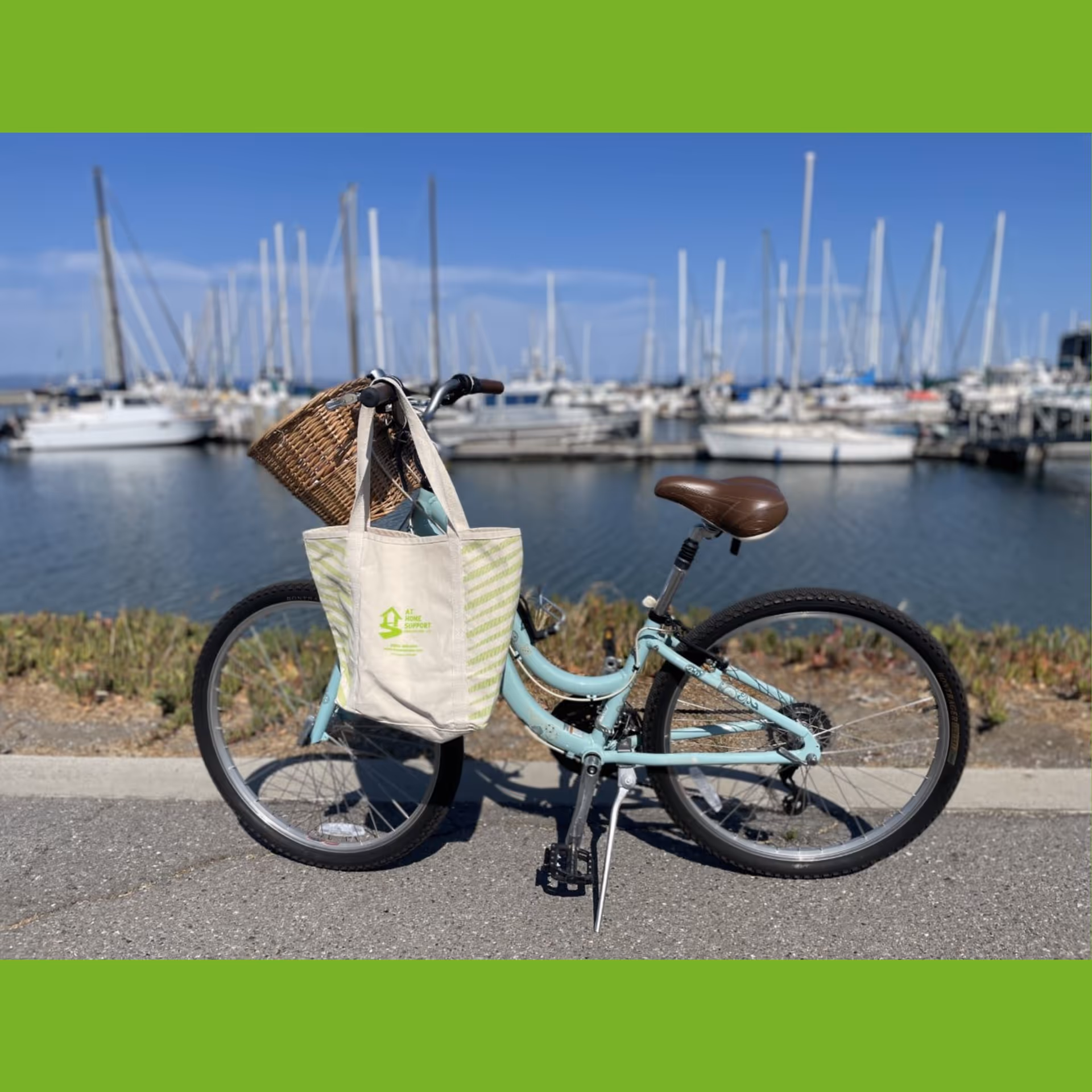 Mint-green bicycle with a basket by a marina full of sailboats.