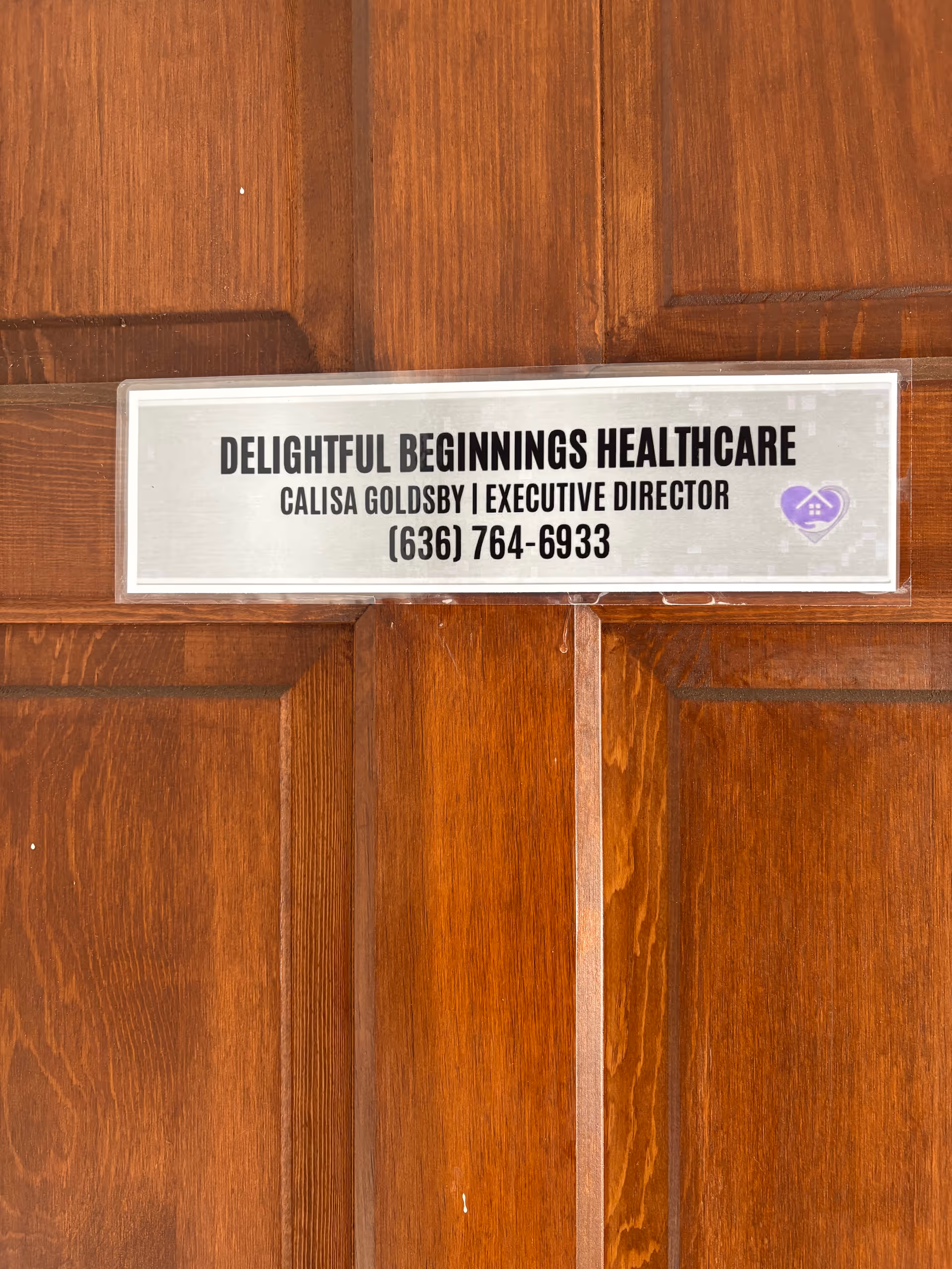 Wooden door features a metal plaque for Delightful Beginnings Healthcare with contact details.