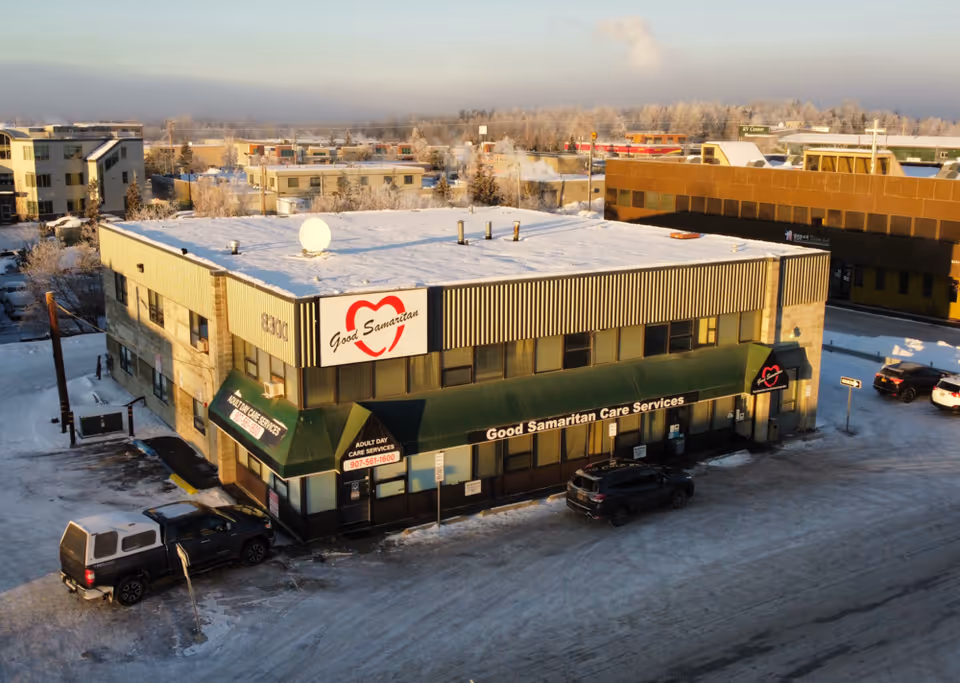 Exterior view of a two-story Good Samaritan Care Services building with snow and parked cars.