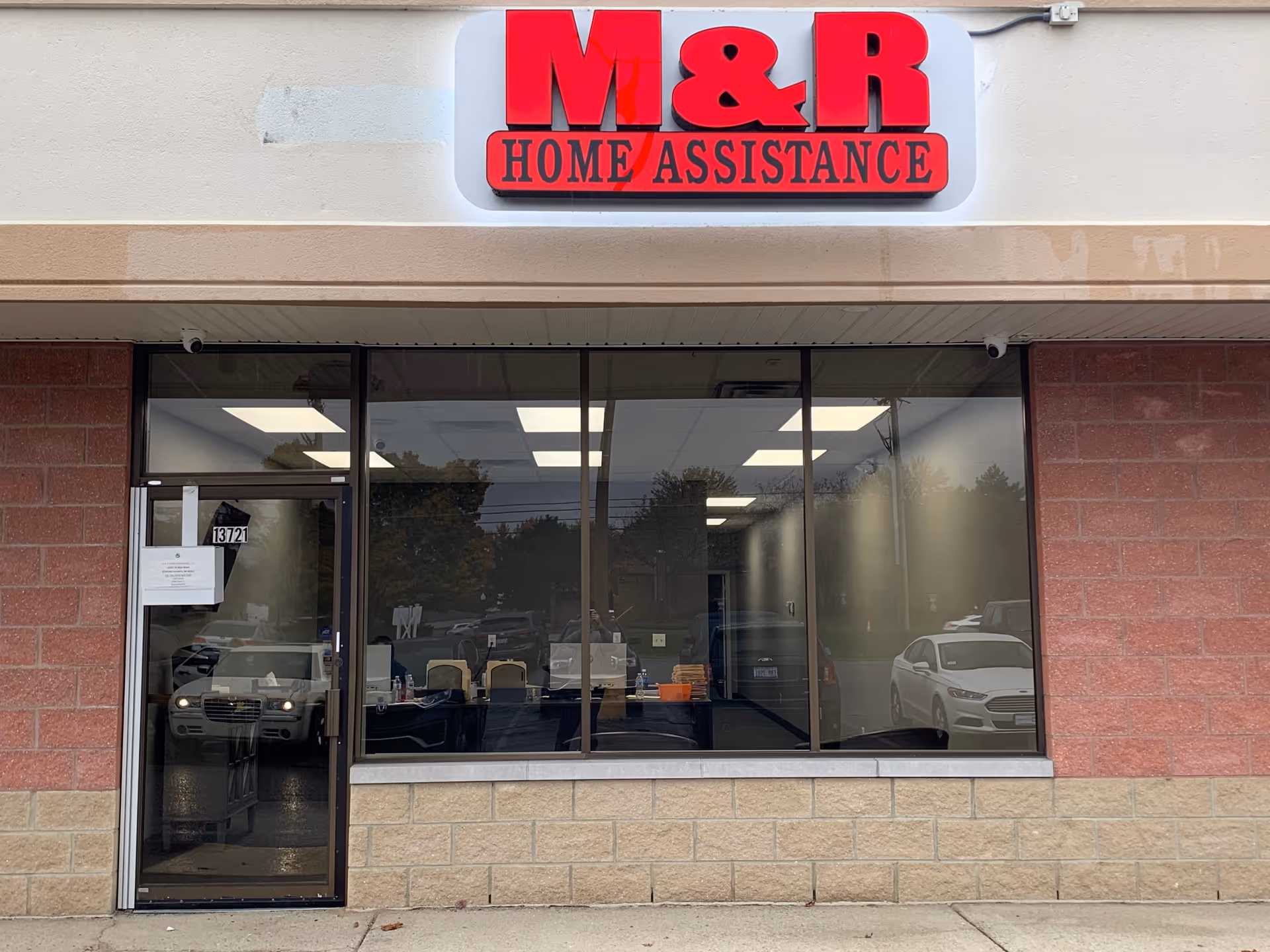 Storefront of M&R Home Assistance with glass windows and a red sign.