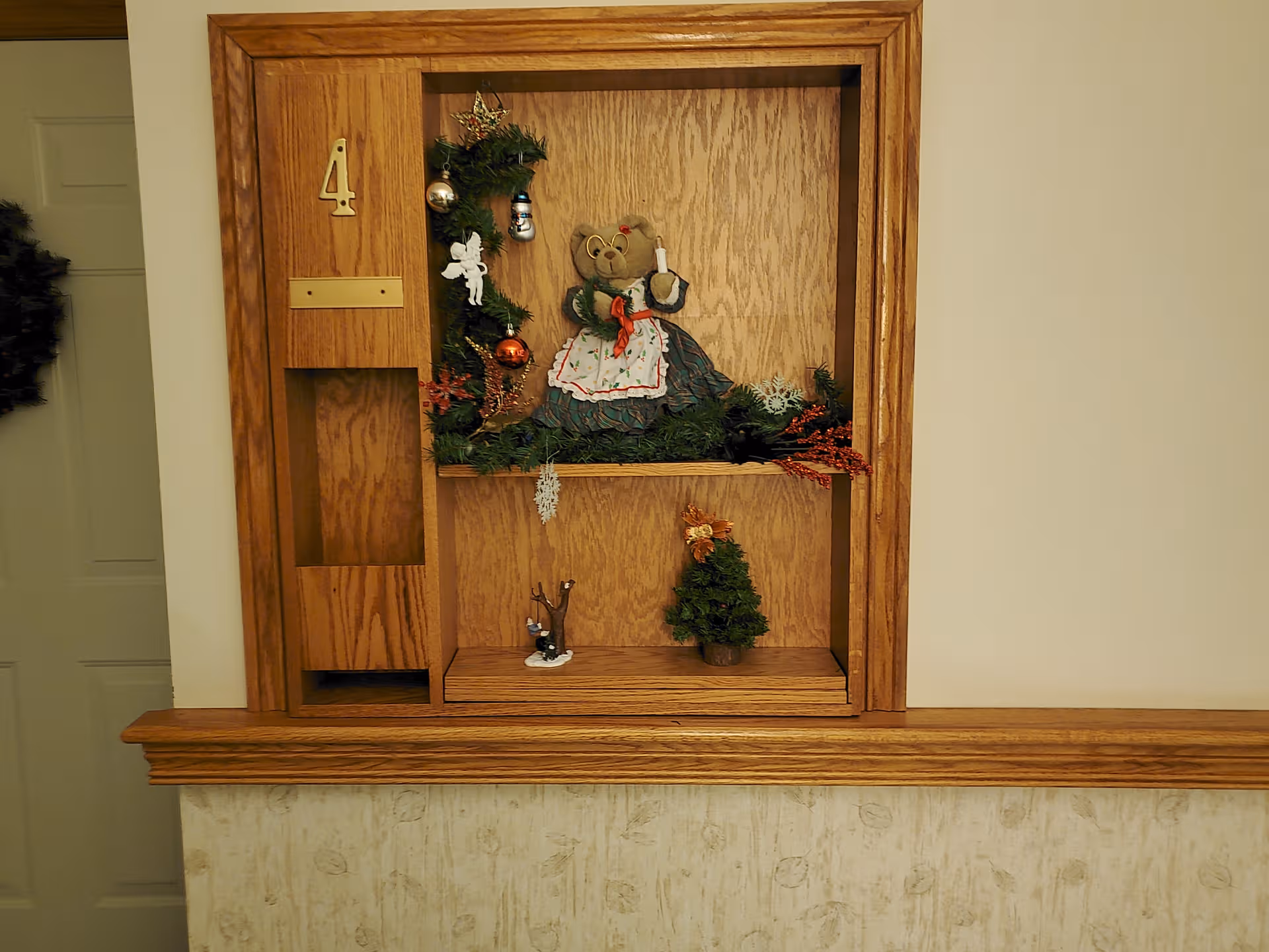 Wooden display cabinet with Christmas decorations sits in a hallway of a senior living facility.