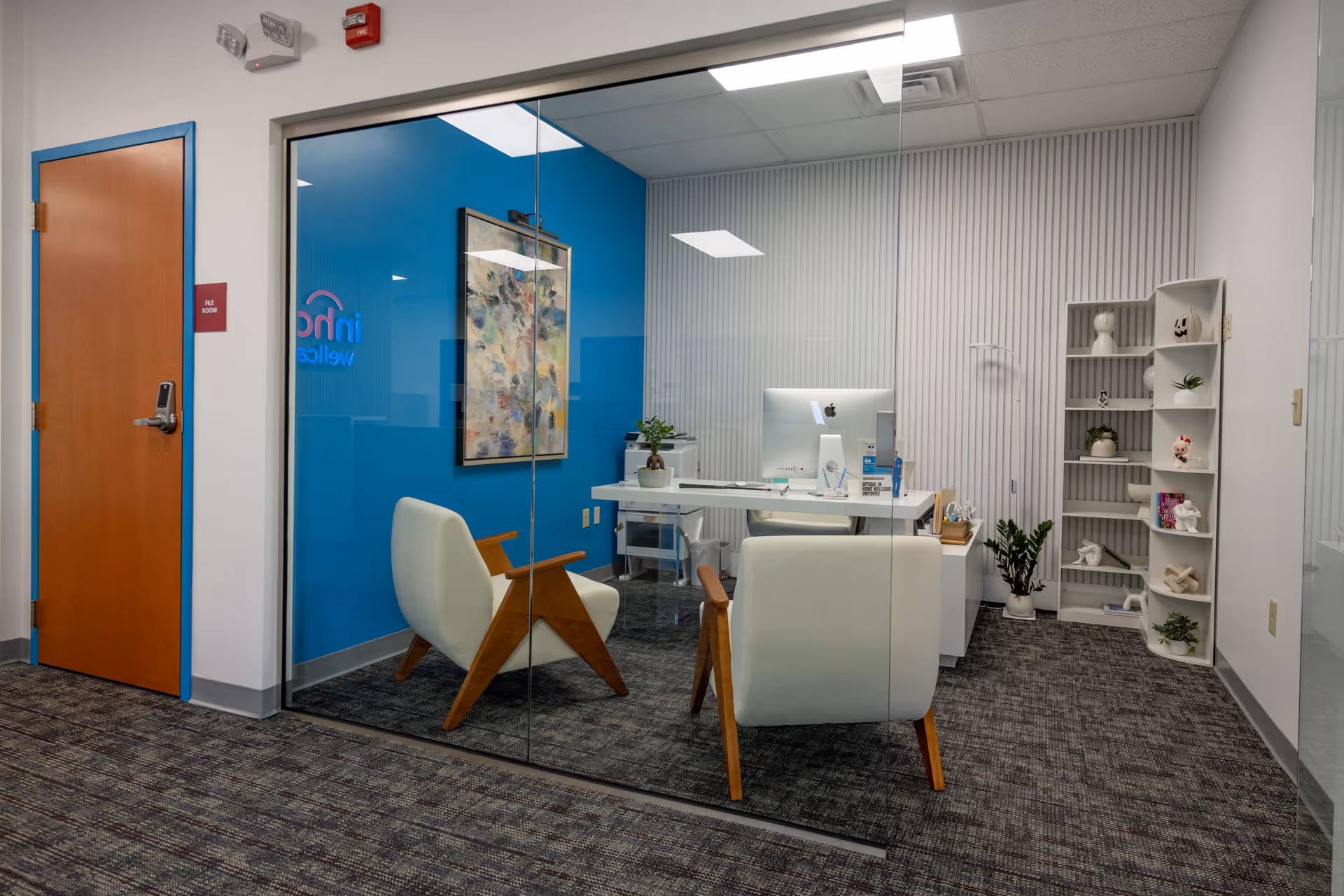 Glass-walled reception area featuring a desk, blue wall, and modern chairs.