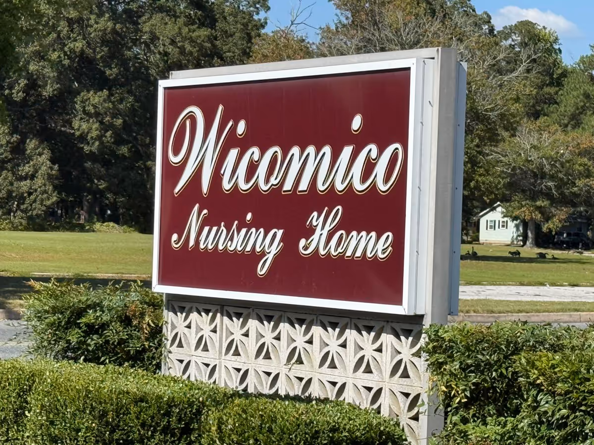 Maroon sign reading Wicomico Nursing Home sits on a decorative base near green lawn.