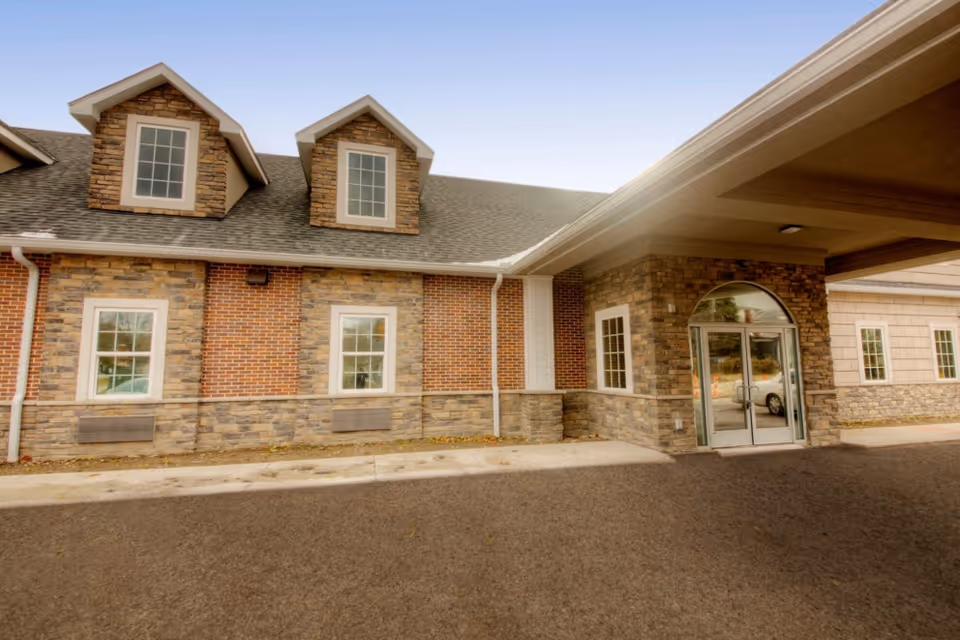 Exterior view of Meadows Assisted Living and Care Campus, brick and stone walls, glass entry doors.