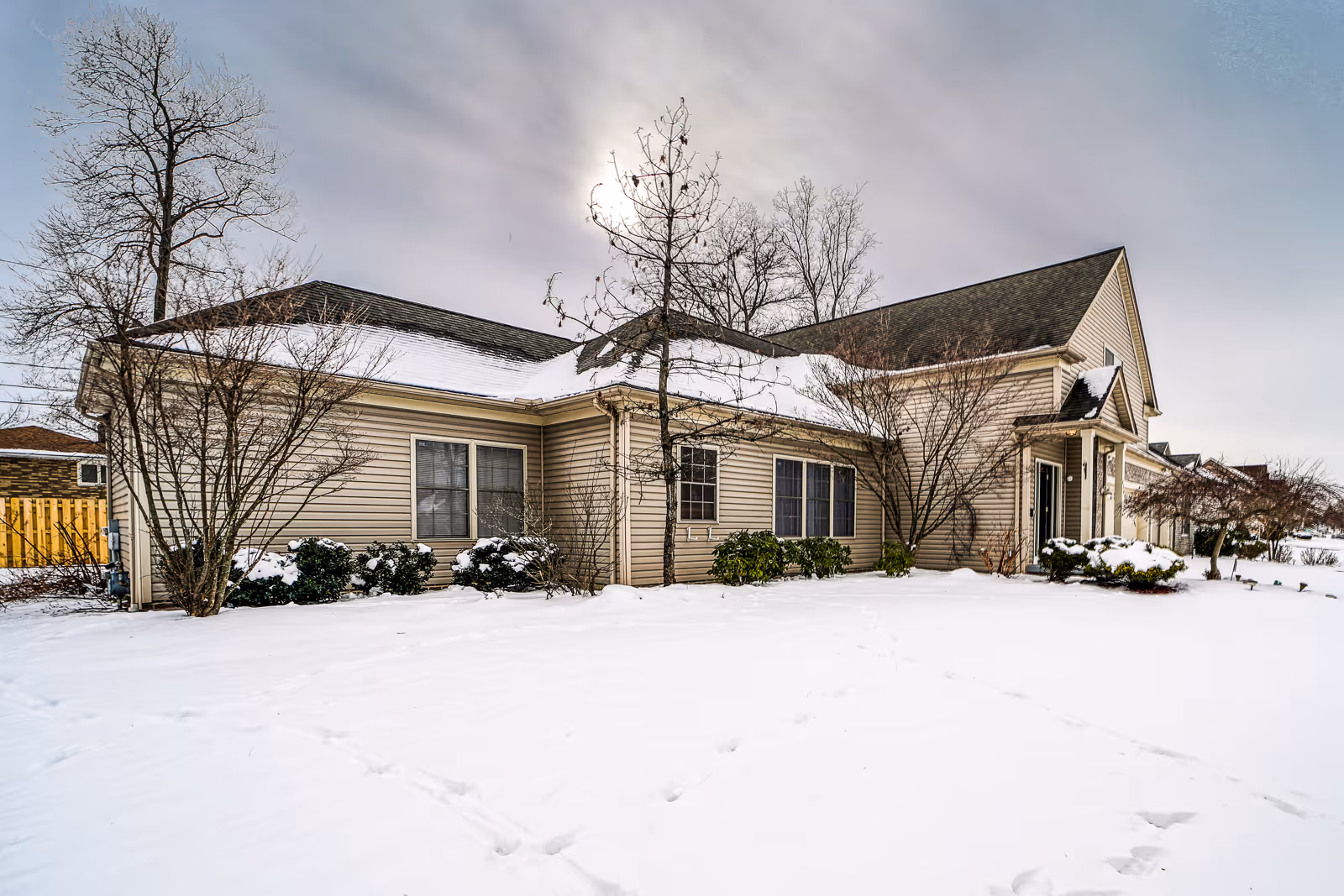 Exterior view of Heritage at Seven Hills, a beige ranch style senior living facility in snow.