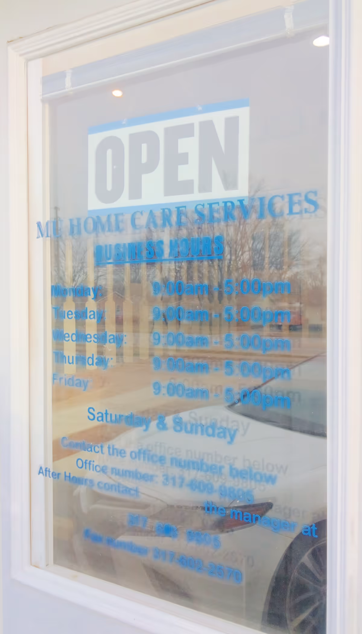 Open sign on glass window displaying MU Home Care Services business hours.