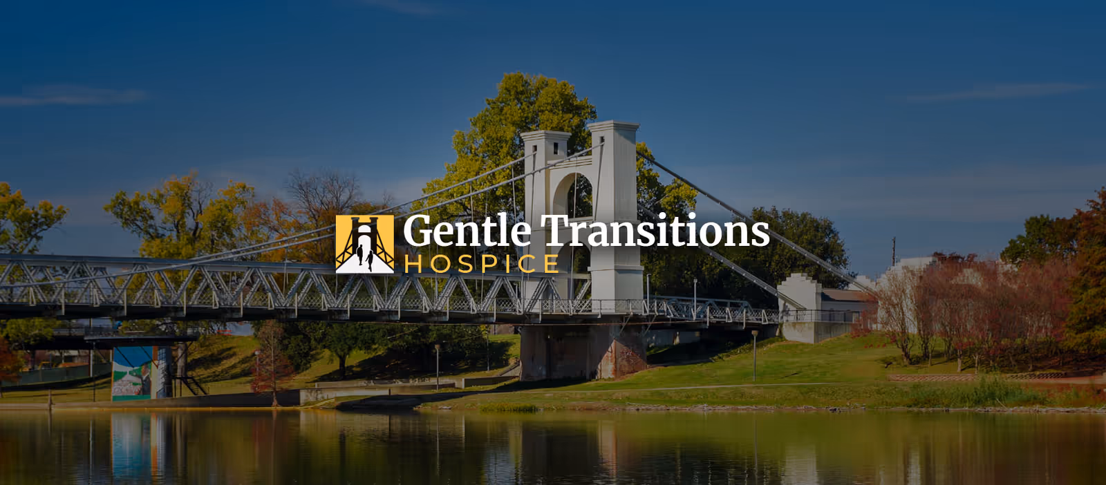Bridge over a river with trees and Gentle Transitions Hospice logo across the center.