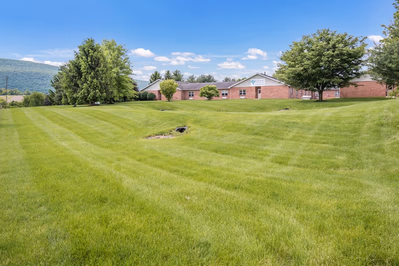 Wide, green lawn in front of Celebration Villa of Reedsville brick building.