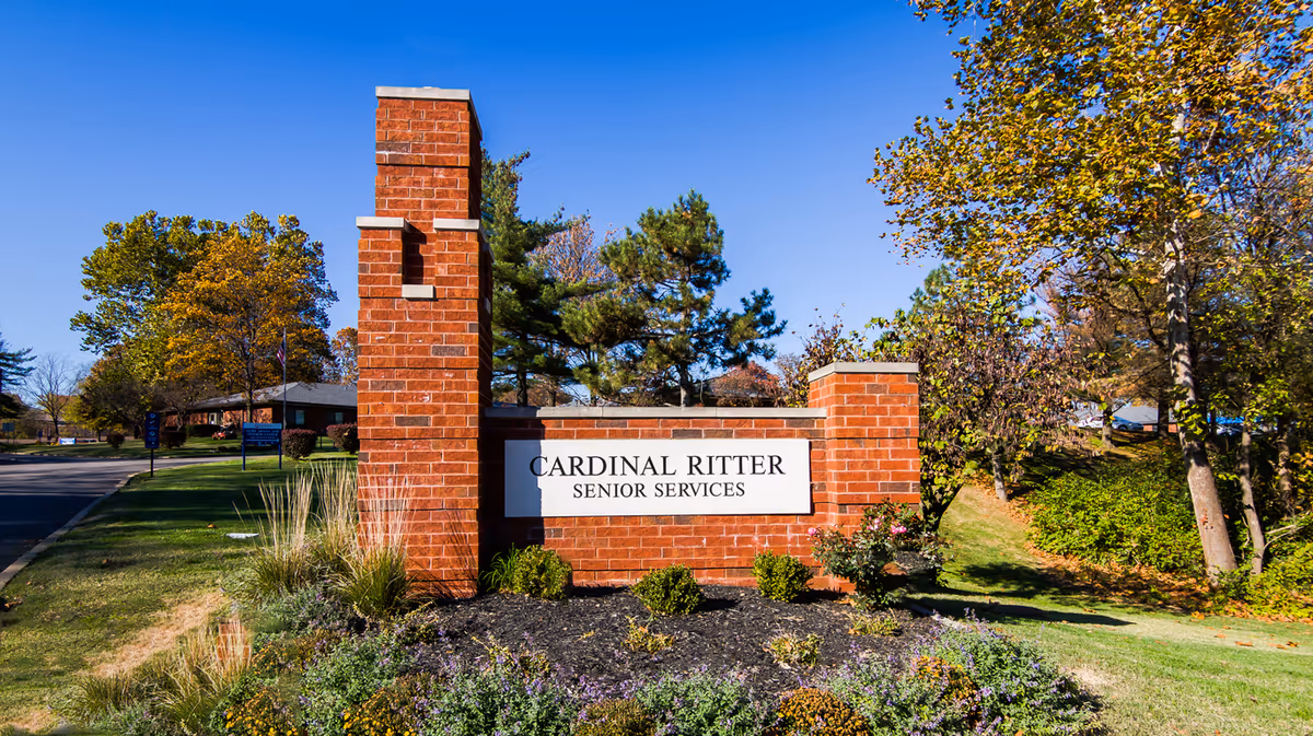 Brick sign reading Cardinal Ritter Senior Services beside landscaped lawn and trees
