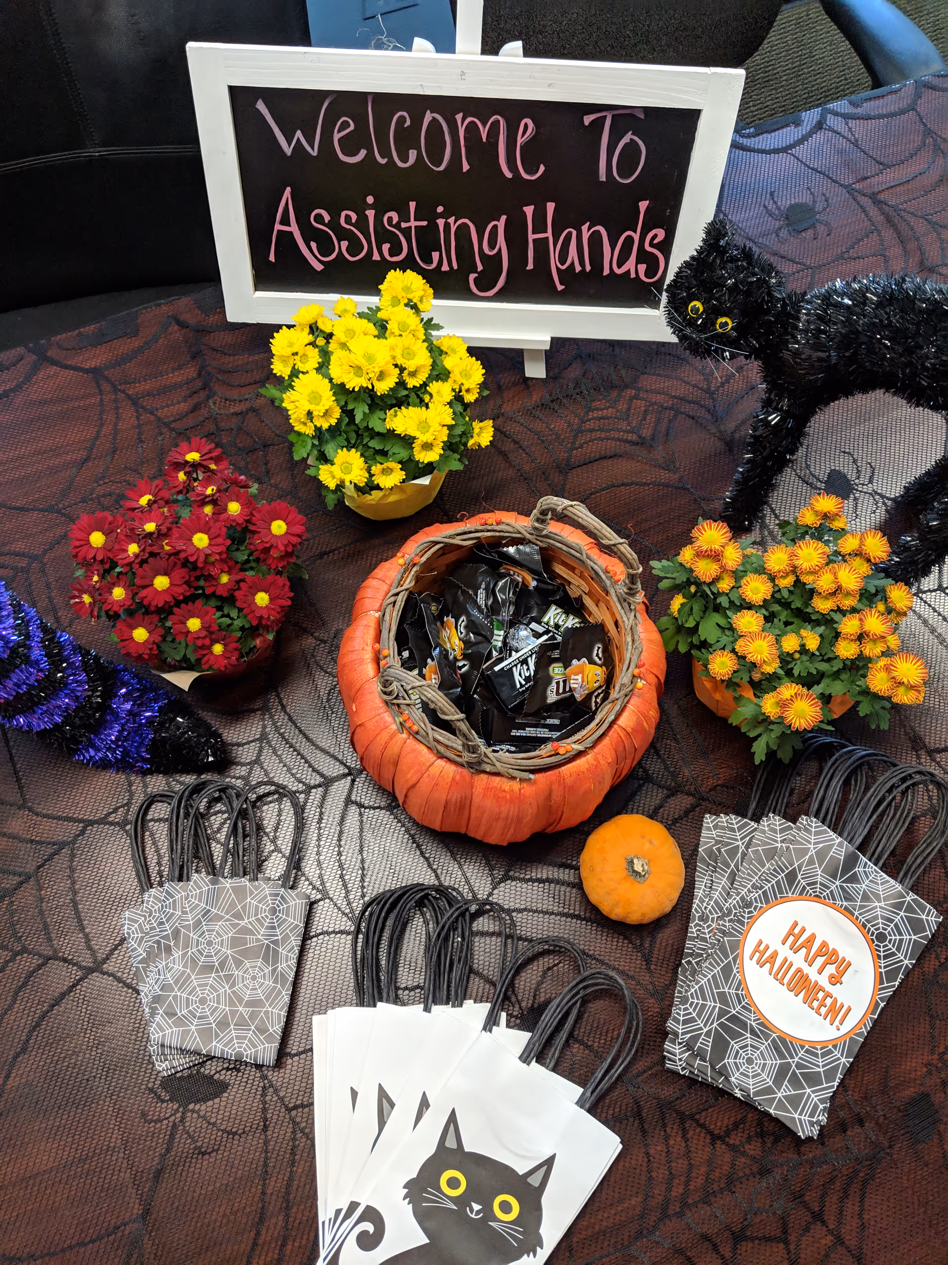 Indoor Halloween display at Assisting Hands with welcome sign, pumpkins, flowers, and gift bags.