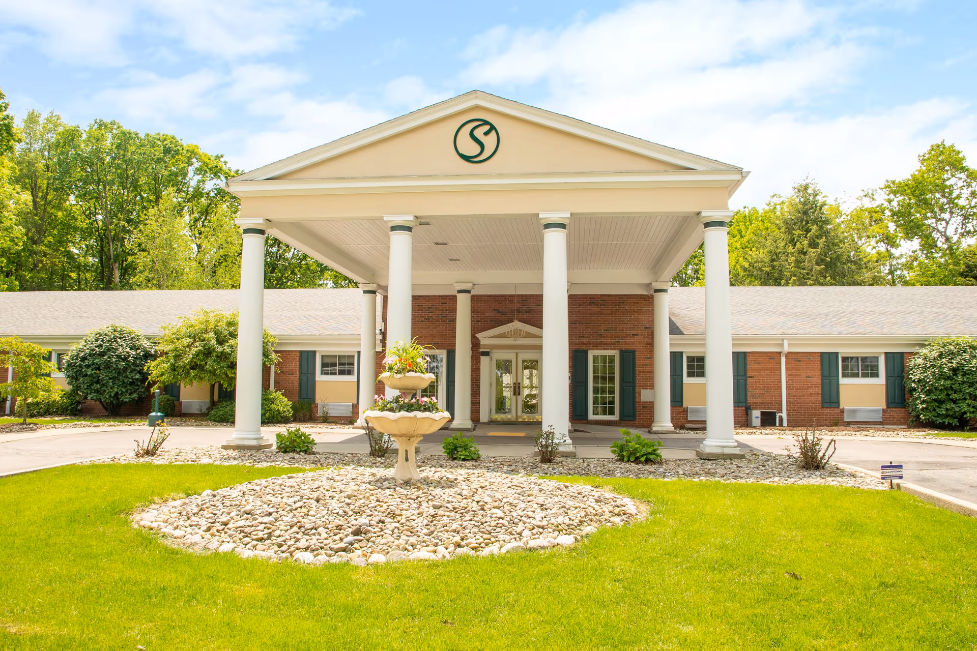 Front view of Strafford Care Center with a columned porte-cochère and circular stone fountain.