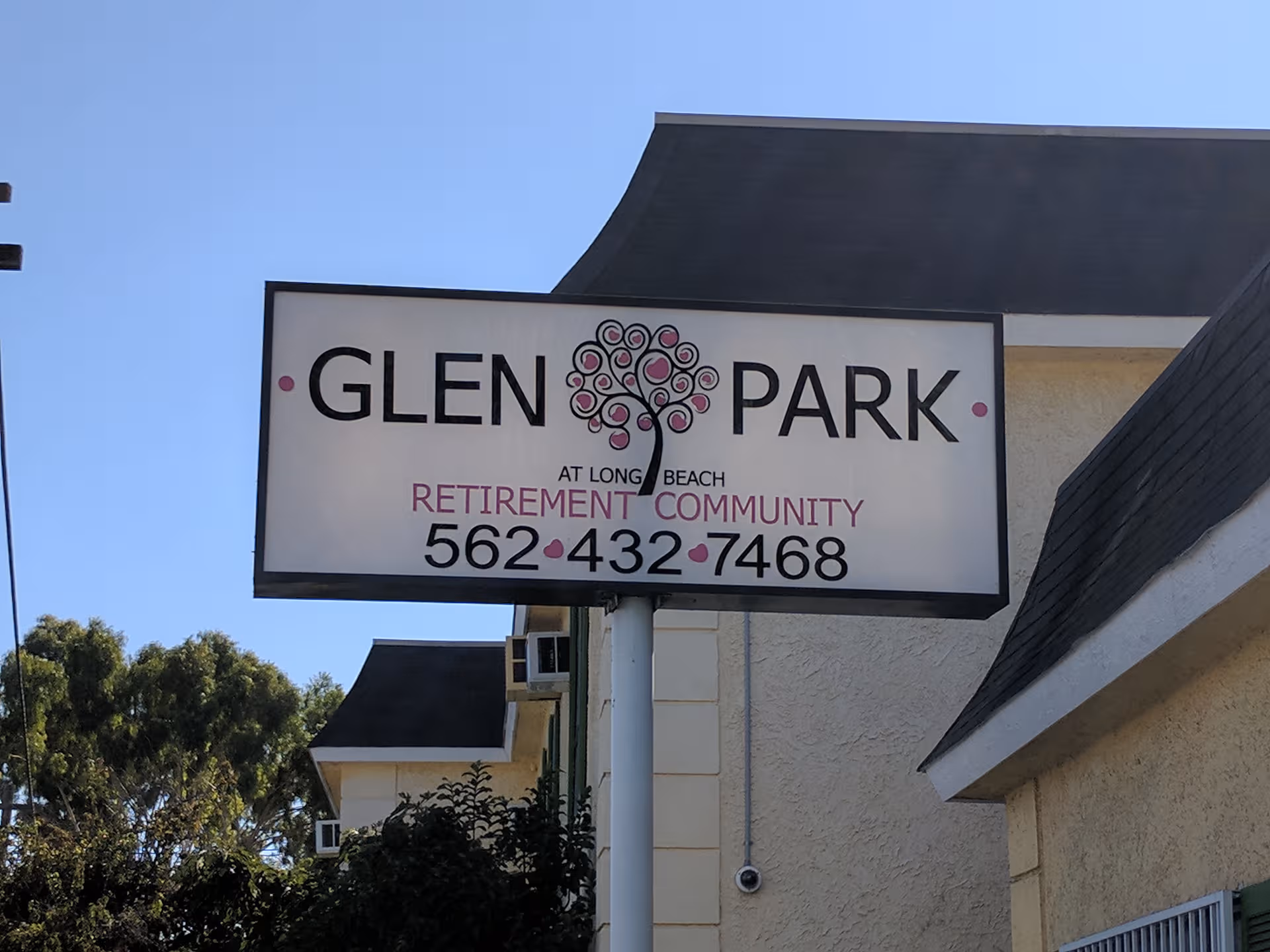 Large Glen Park retirement community sign on a white post in front of a beige building.