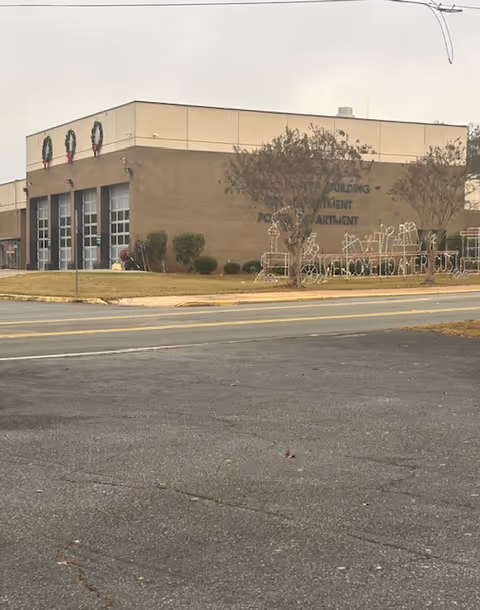 Exterior view of a tan brick building with wreaths along the front.