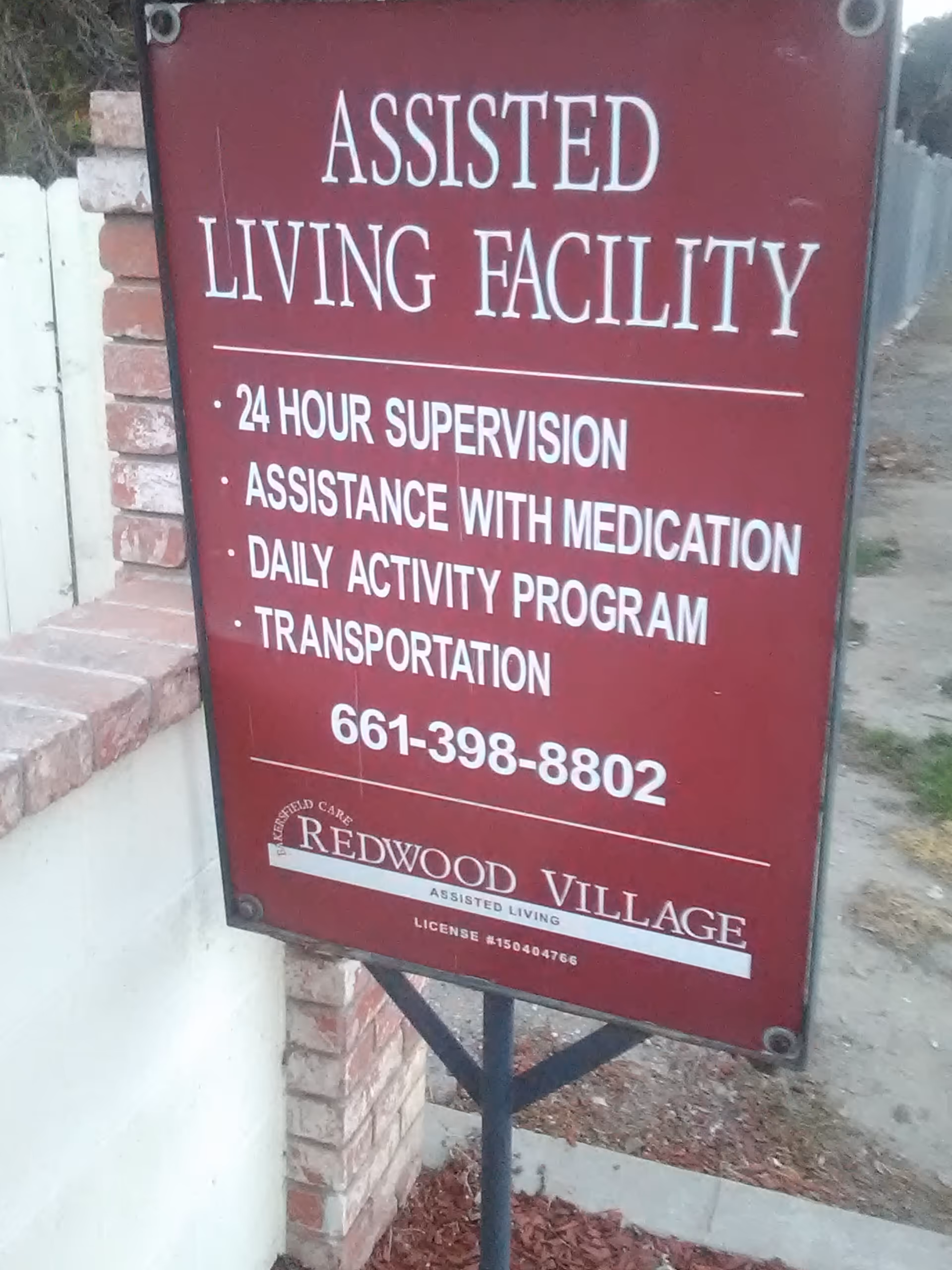 Outdoor sign advertising an assisted living facility with services and contact information.