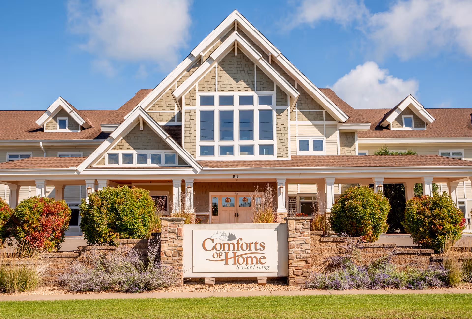 Exterior view of Comforts of Home senior living building with landscaped entry.
