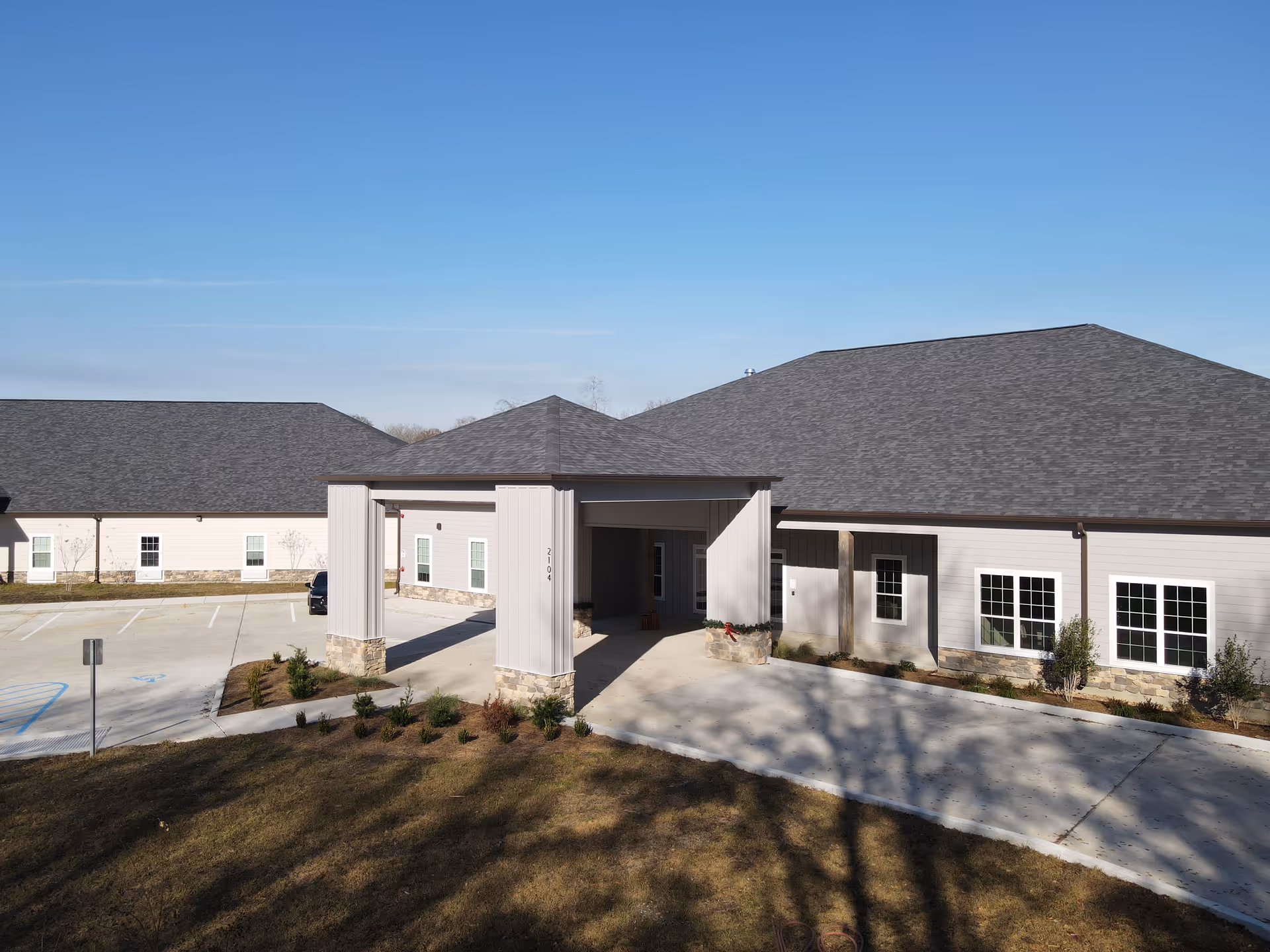 Exterior view of a single-story senior living building with a covered entrance and parking.