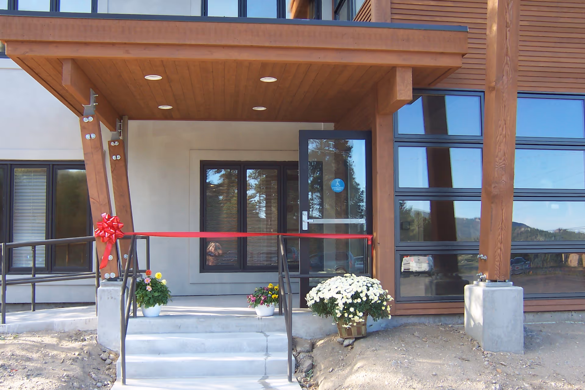 Exterior facility entrance with a red ribbon and potted flowers