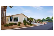 Exterior view of Clark Residence senior living facility with curved driveway and landscaped surroundings.
