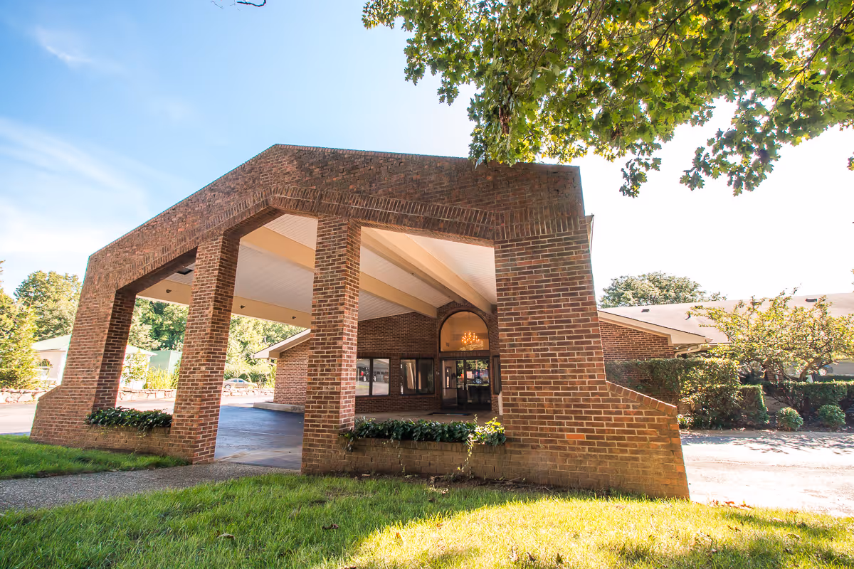 Brick building with a covered front entrance and surrounding landscaping.