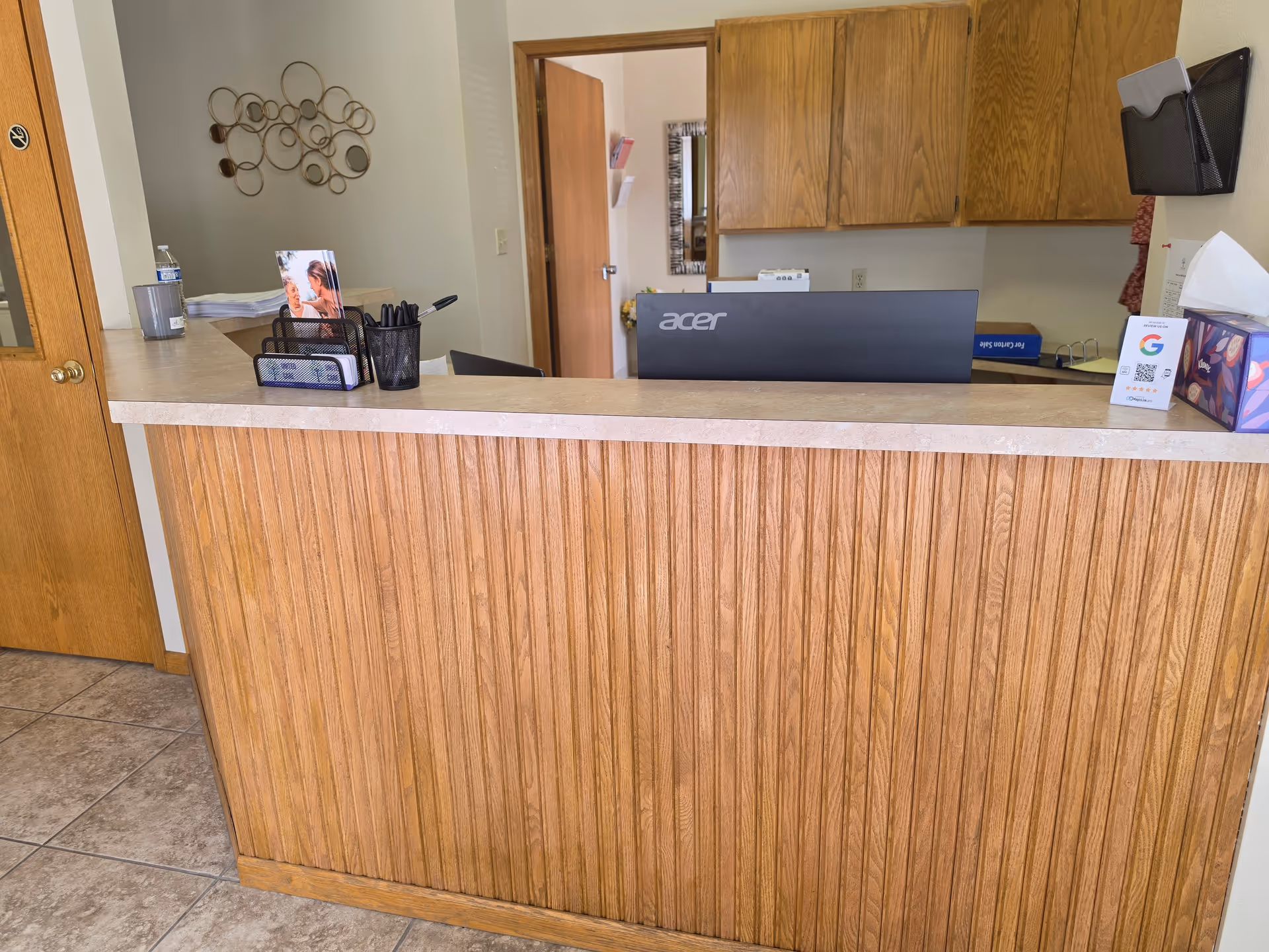 Wood-paneled front desk area with computer monitor and office supplies inside a facility.