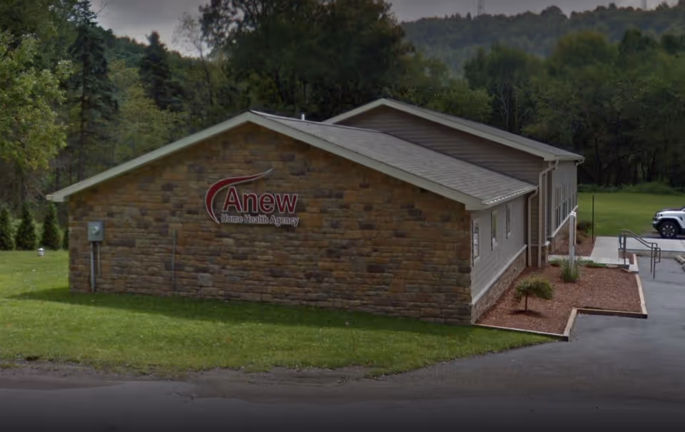 Single-story stone facility with Anew Home Health Agency sign and landscaping.