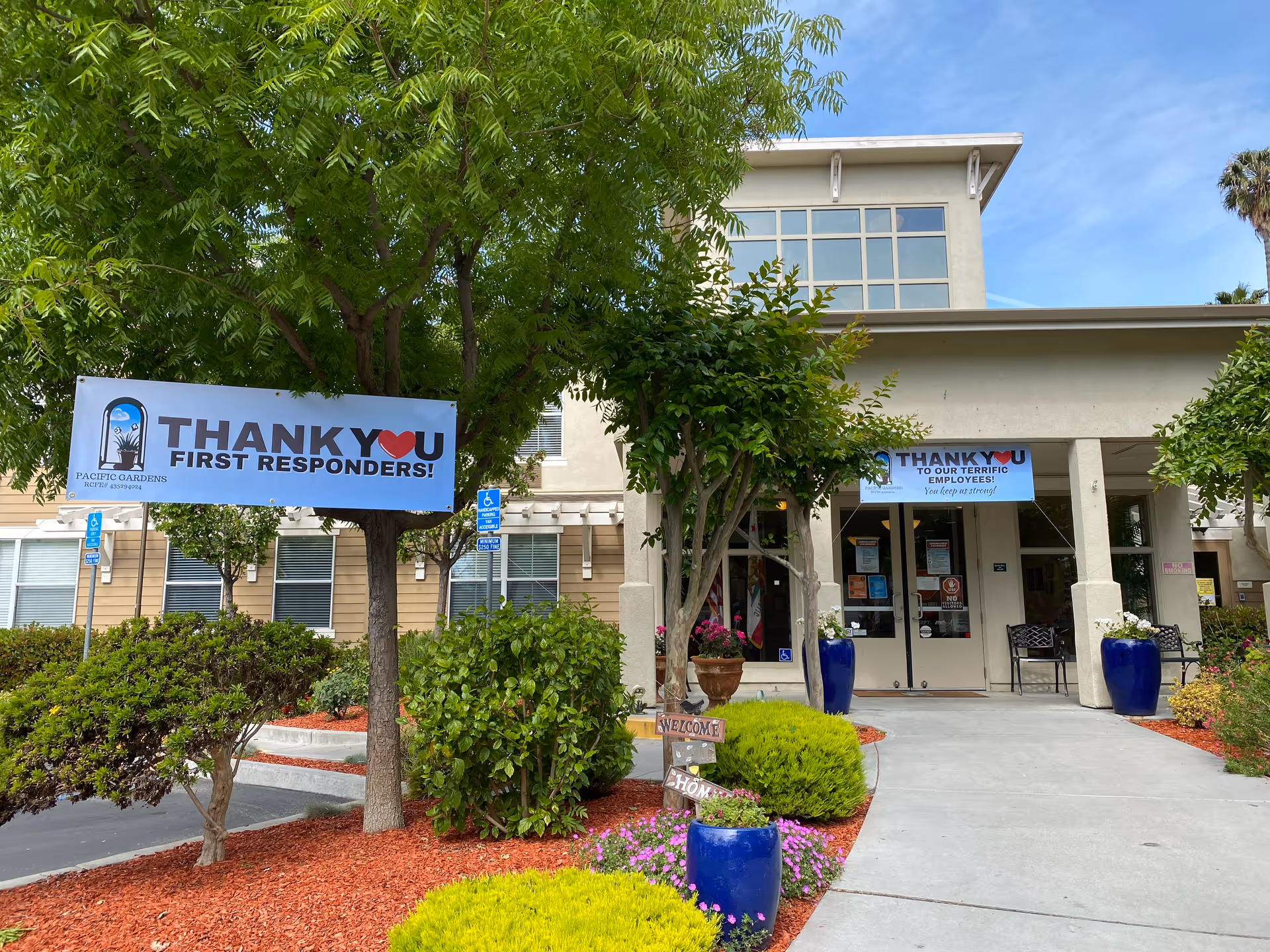 Exterior view of Pacific Gardens entrance with banners and landscaped walkway