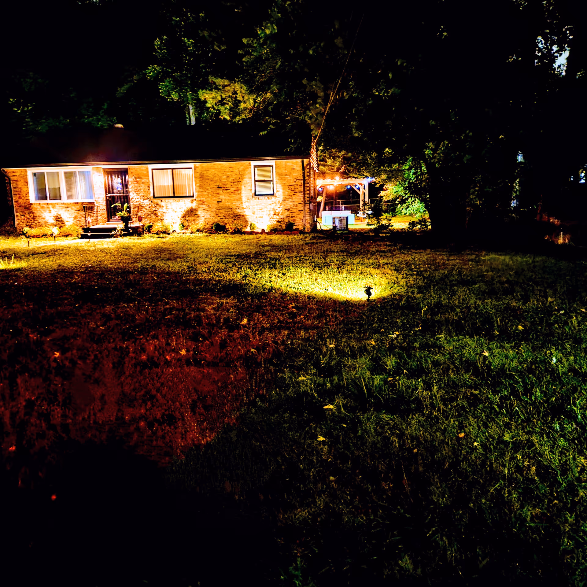 A single-story brick senior care home at night, illuminated by yard lights.