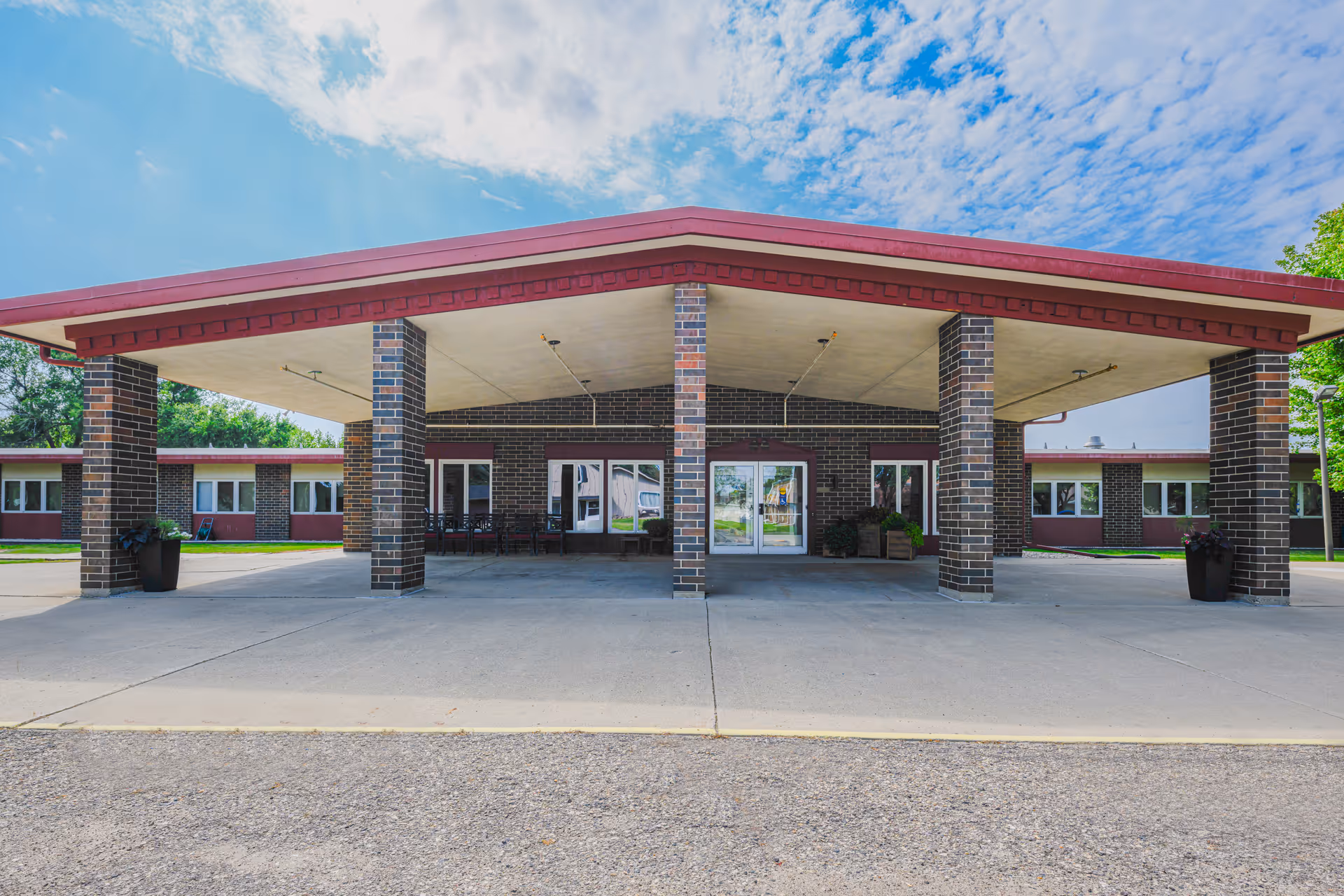 Brick senior living facility entrance with a large covered drop-off area and glass doors.