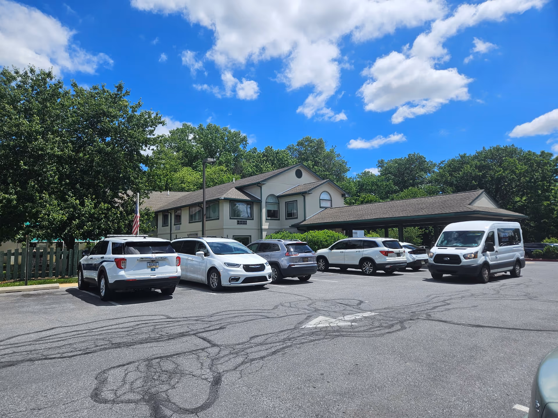 Exterior view of Naamans Creek Country Manor with a parking lot and trees.