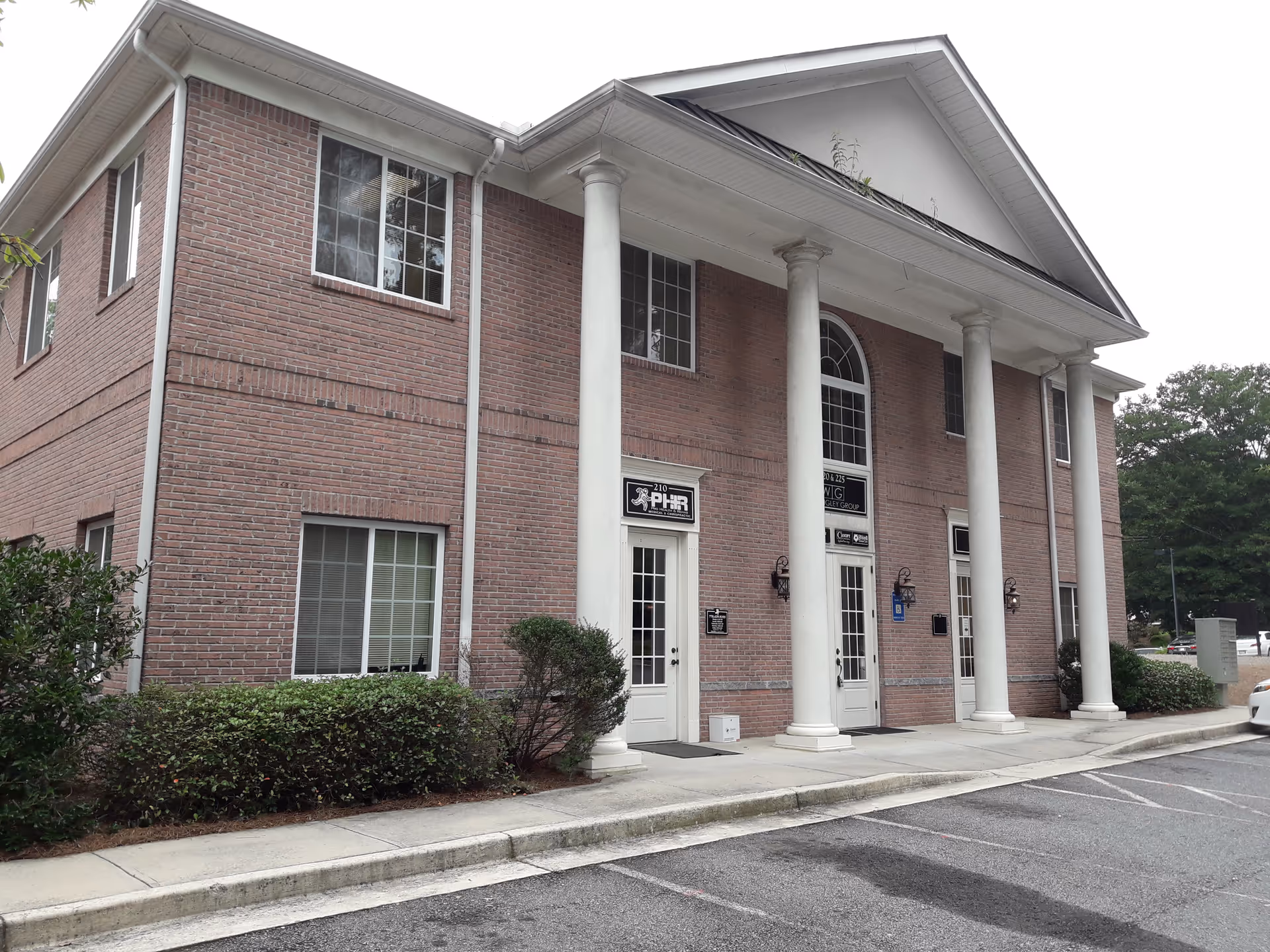 Exterior view of a brick building with tall white columns and arched entryway.