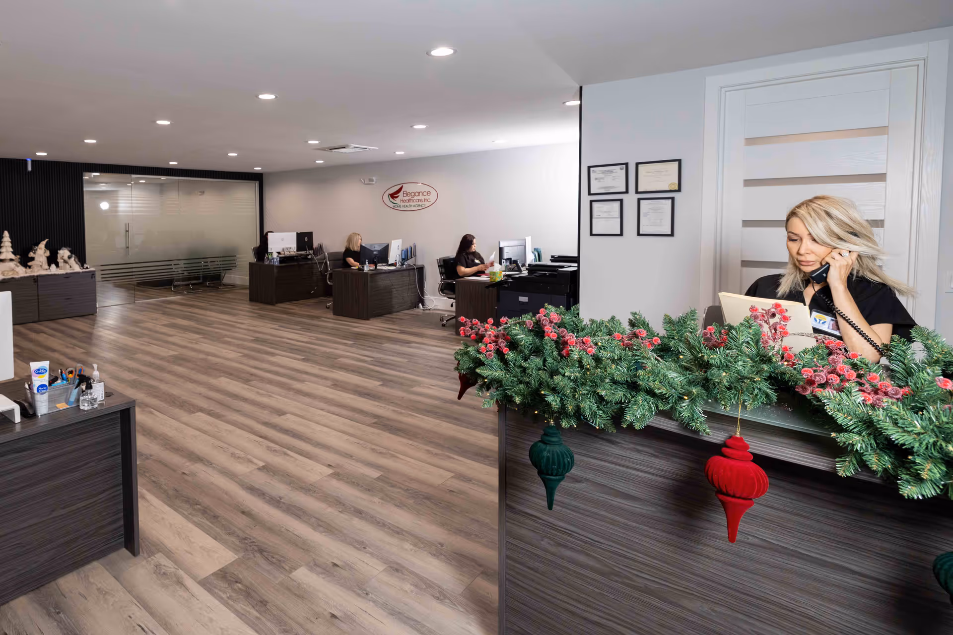 Bright reception area with a front desk, garland, and staff at computer desks.