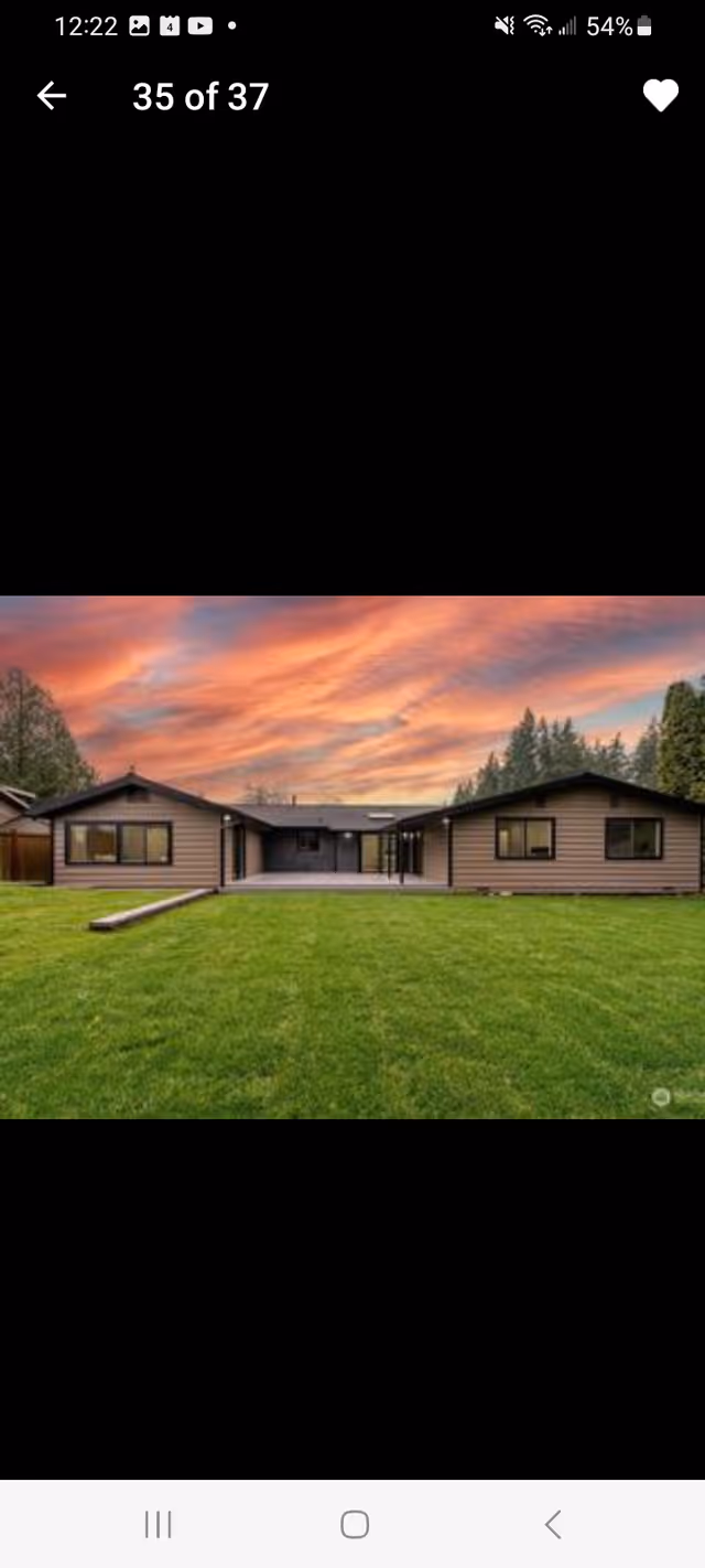 Front view of a single-story adult family home with a green lawn and sunset sky.