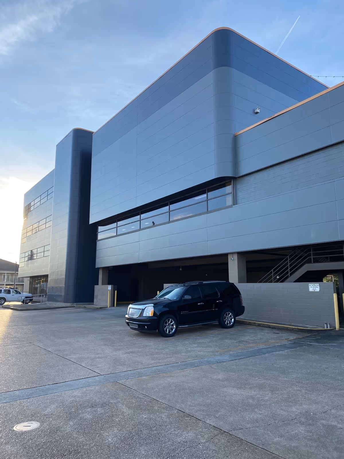Modern gray-blue exterior of a senior living facility with a parked black SUV.
