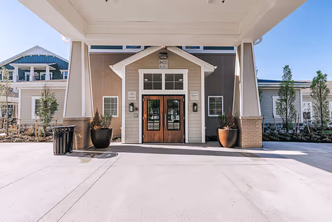 Front entrance of The Barrymore senior living facility with double wooden doors and covered drop-off.