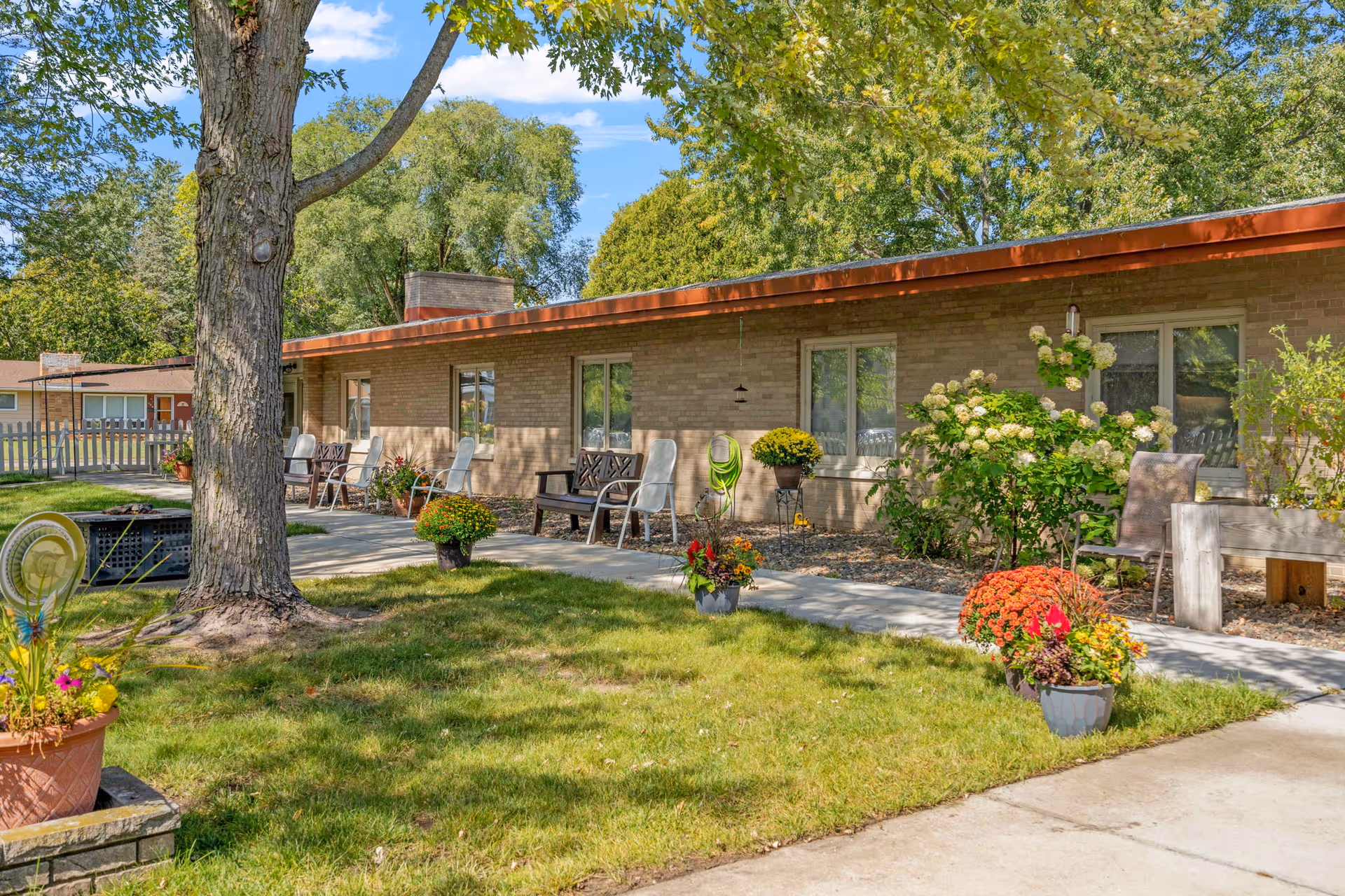 Exterior of Elim Home Milaca with a front patio, chairs, and blooming potted plants.